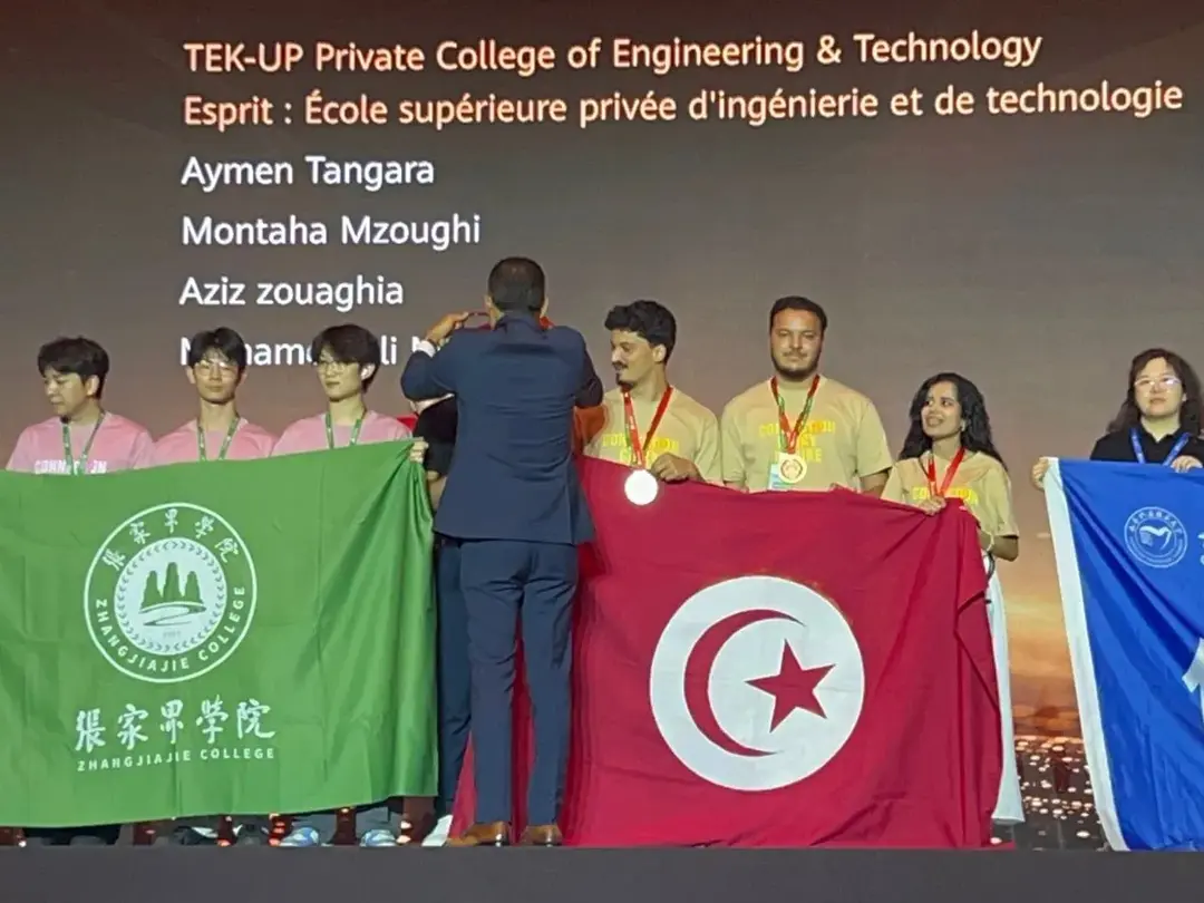 Receiving the medal on stage with the TEK-UP team name displayed behind